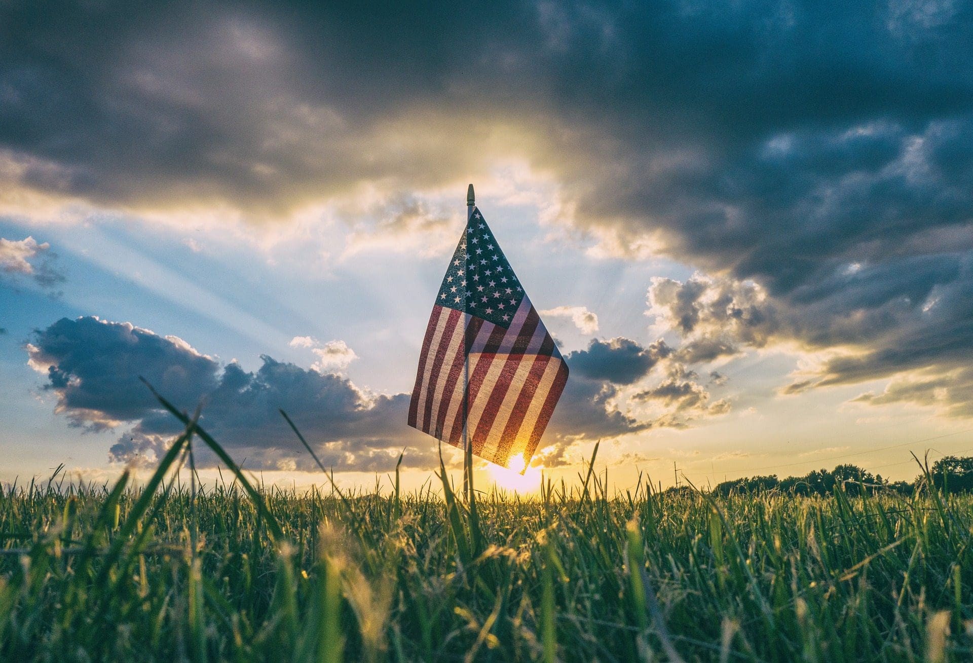 blog picture of american flag in a field during sunset