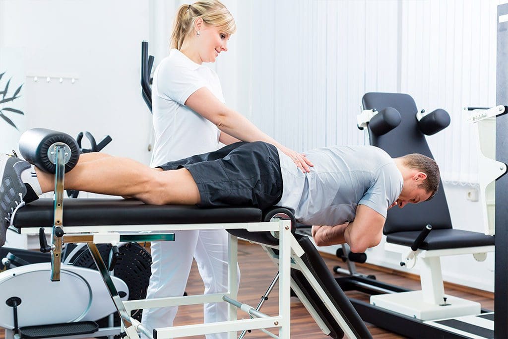 Imagen de un profesional de la salud que ayuda al paciente a realizar ejercicios para el dolor lumbar y la ciática.